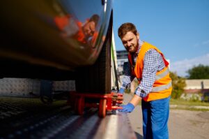 Flatbed tow truck operator fixing the car on platform